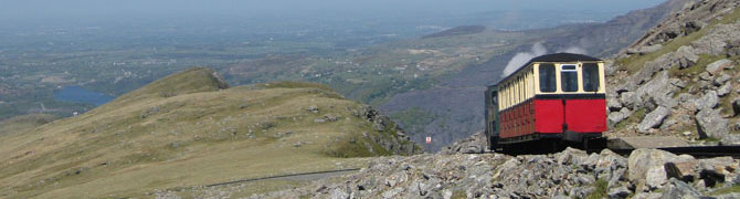 A view of the Snowdon Mountain Railway train as it descends Mount Snowdon, with Llyn Padarn in the distance.